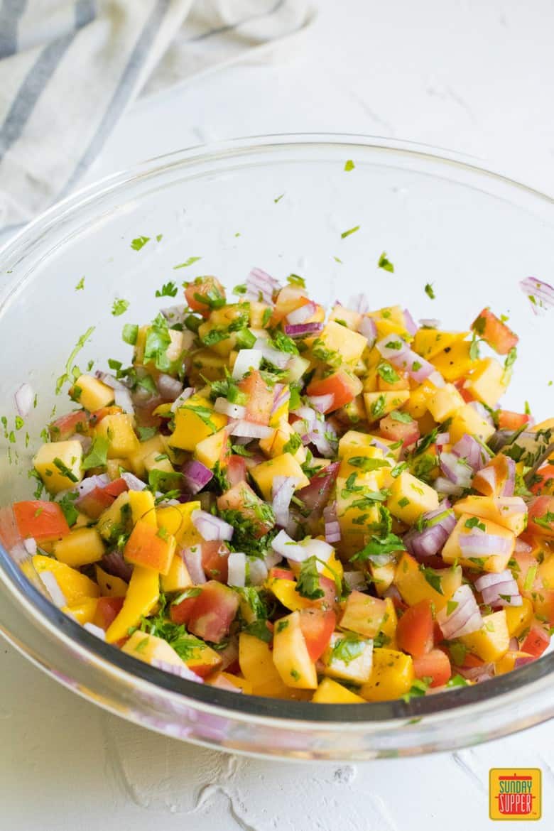 peach mango salsa ingredients mixed up in a clear bowl ready for serving