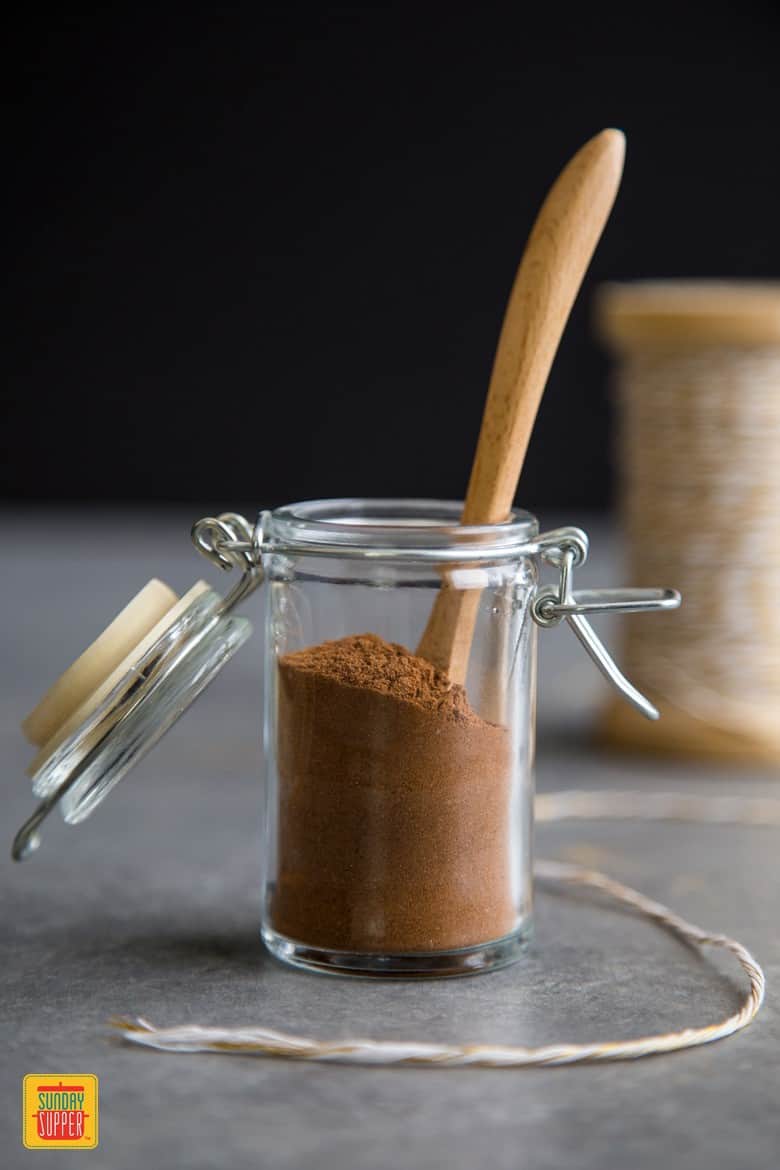 Pumpkin Pie Spice Recipe in an open glass jar with a tiny wooden spoon inside