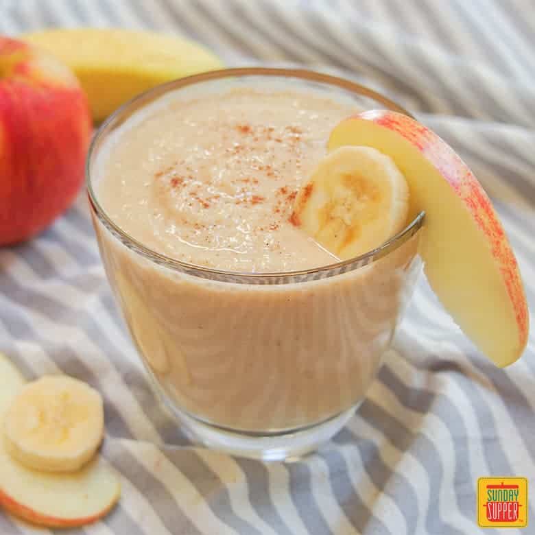 apple banana smoothie in a glass with an apple and banana slice