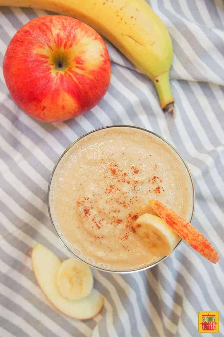 apple banana smoothie in a glass with apple and banana slices