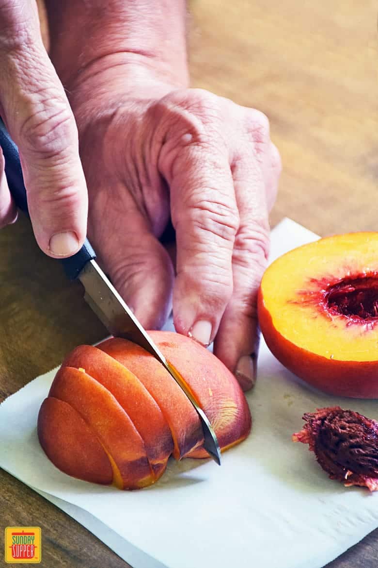 How to cut peaches: slicing the peach into slices on a white cutting board