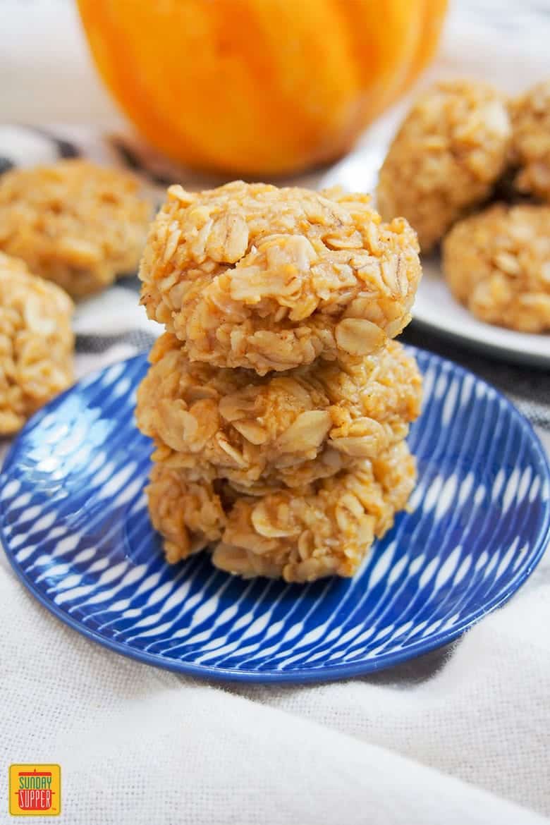 Three no bake pumpkin cookies stacked on a blue plate