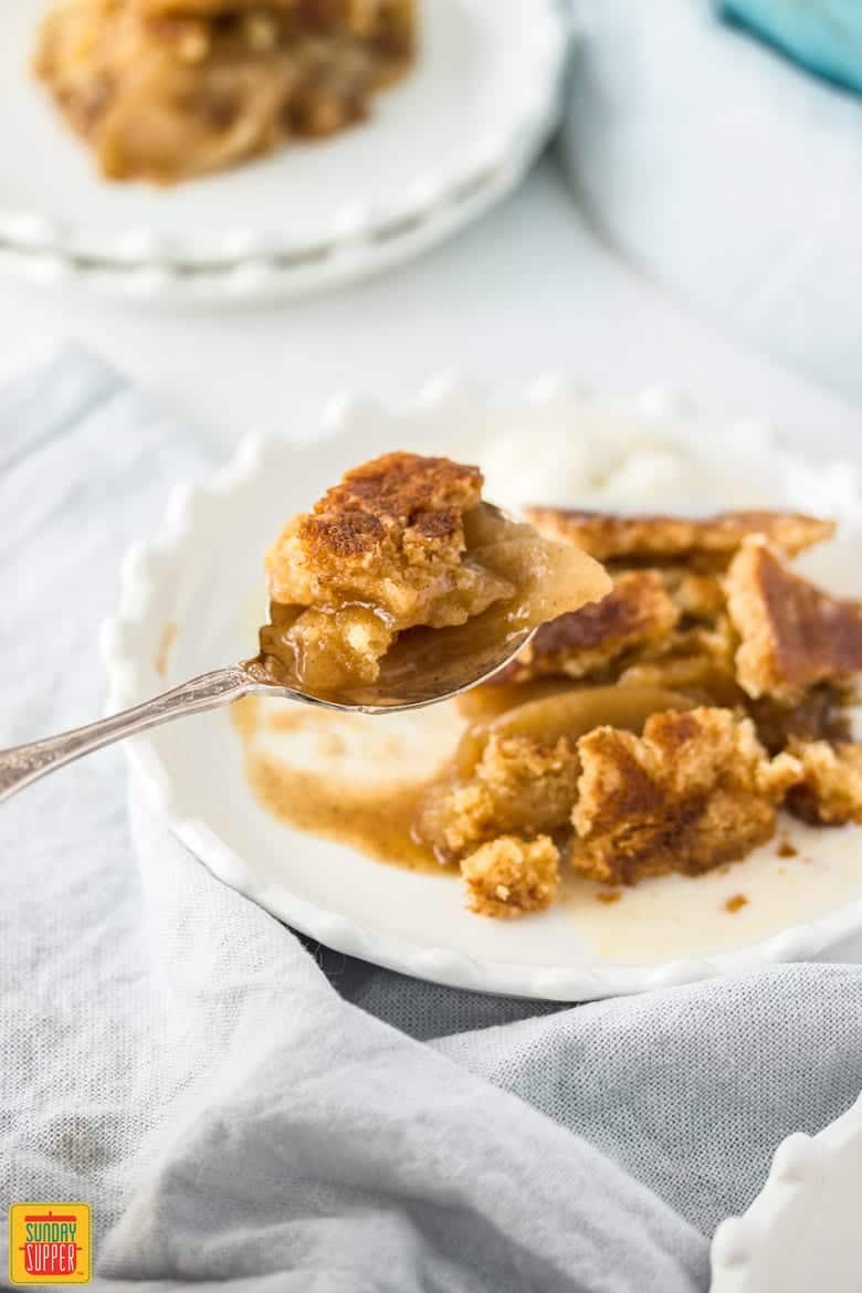Apple Dump Cake on a white plate with a spoonful ready to eat