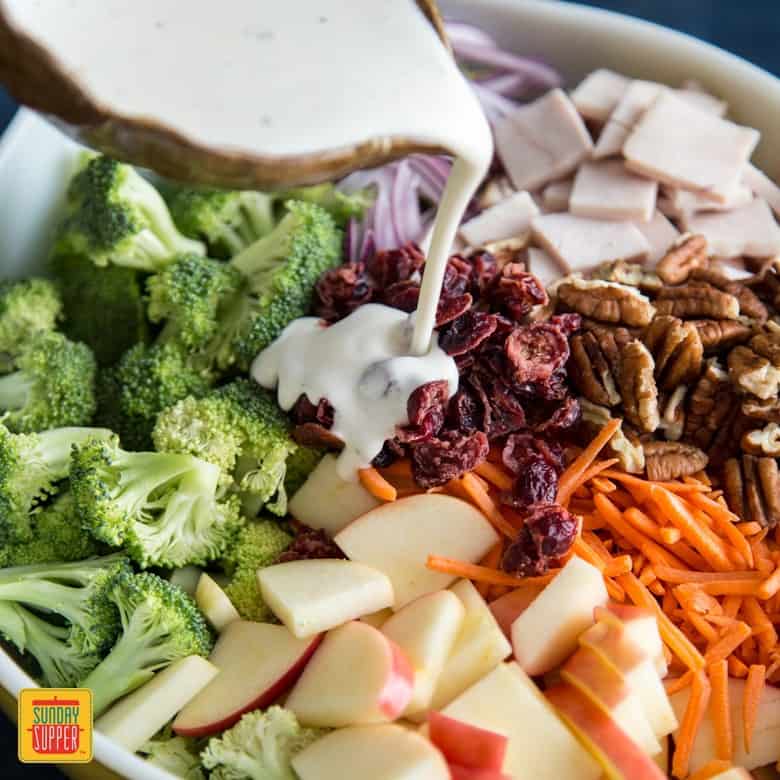 Pouring dressing over broccoli apple salad