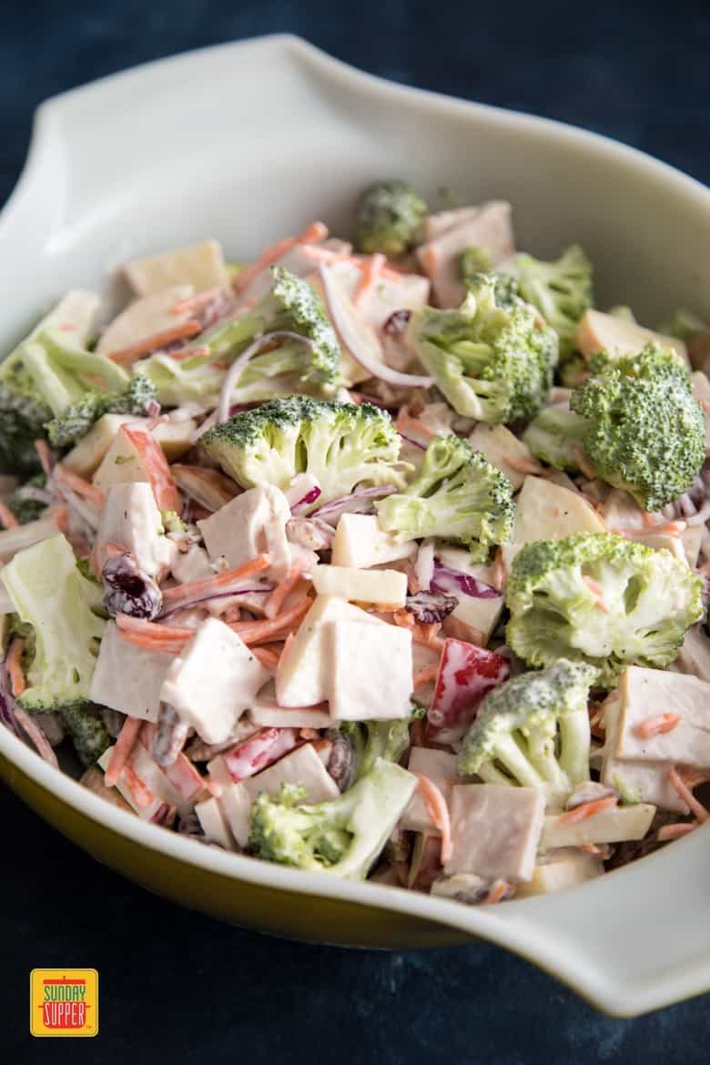 Broccoli apple salad mixed with dressing in a deep bowl with handles