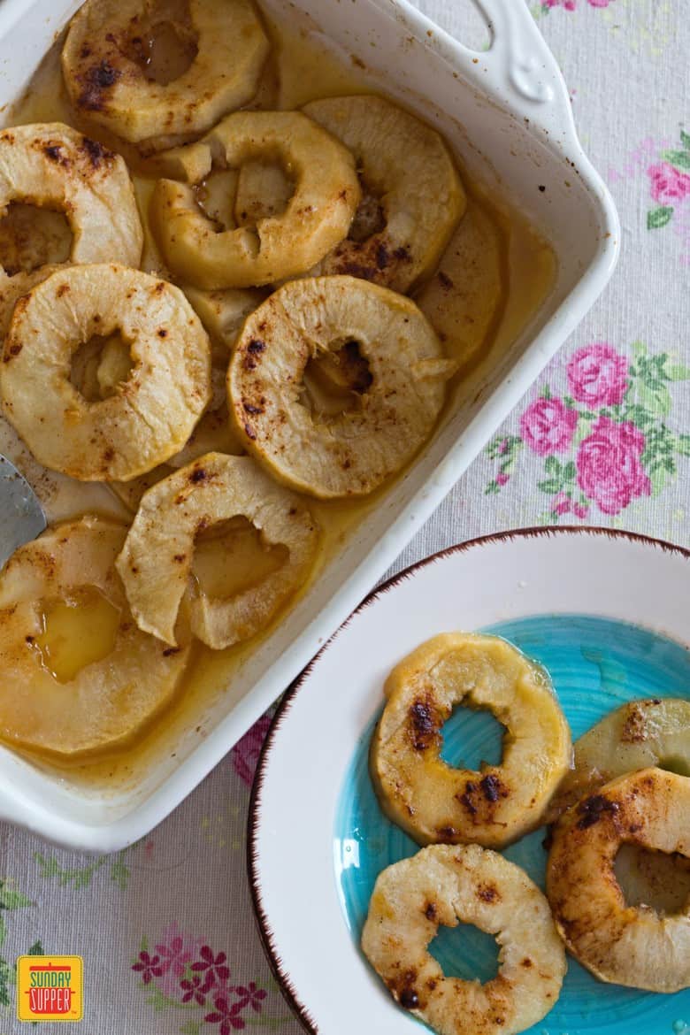 Sliced Baked Apples in a white baking dish and served on a plate
