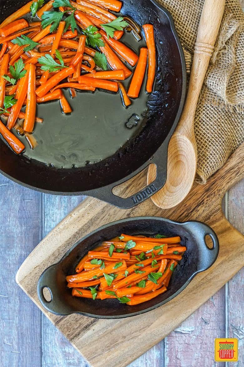 Brown Sugar Glazed Carrots topped with fresh parsley in cast iron skillet