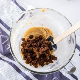 Mixing raisins and cinnamon into oatmeal raisin cookies
