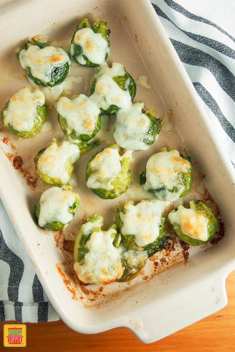 smashed Brussels sprouts in a deep baking dish with cheese on top