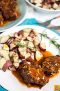Instant pot pot roast on a white plate with potatoes and herbs