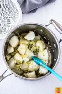 Mixing potatoes into cabbage and onions