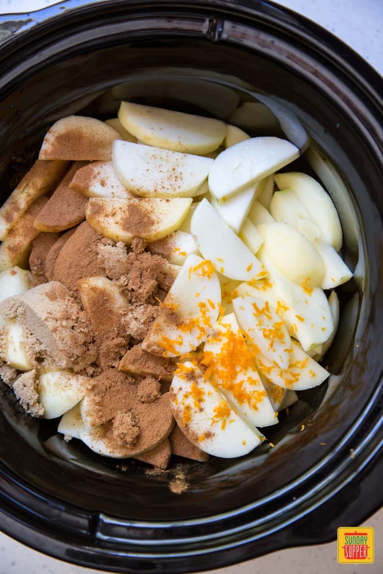 Adding the ingredients for slow cooker applesauce to the cooker