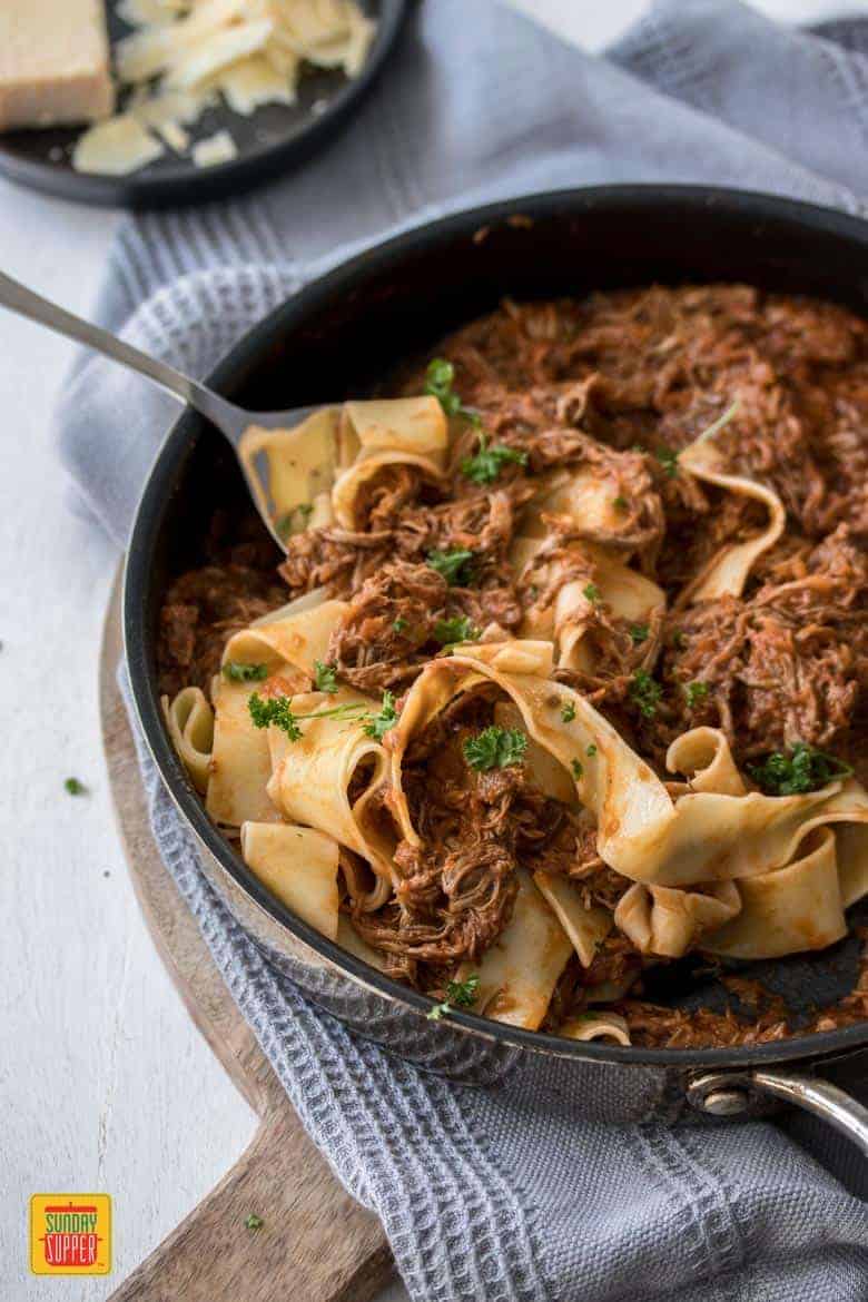 Slow Cooker Beef Ragu with pappardelle pasta being served from a skillet