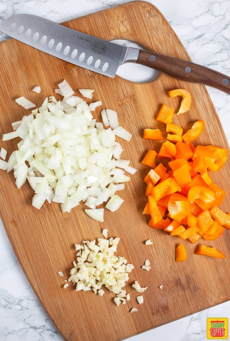 Slow Cooker Vegetarian Chili veggies being diced on a cutting board 