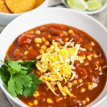 A white bowl of Slow Cooker Vegetarian Chili topped with cheese & cilantro