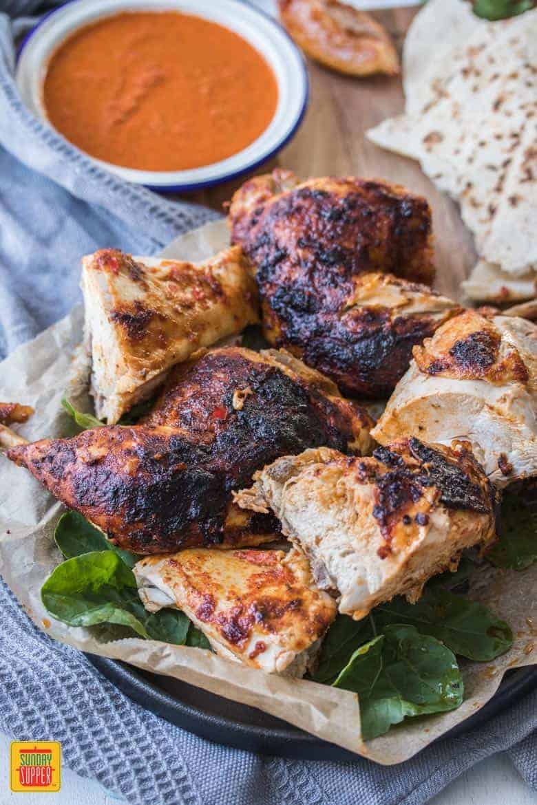 roasted chicken next to a bowl of peri peri sauce