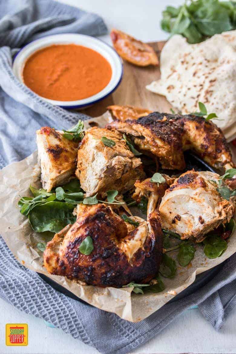 A roasted chicken, perfectly marinated in a simple peri peri sauce, on parchment paper