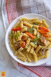 Rasta Pasta Recipe for two with jerk chicken, bell peppers, and fusilli pasta, served on a white plate