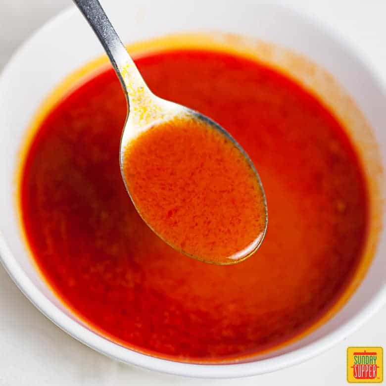 Buffalo sauce in a white bowl with a spoon