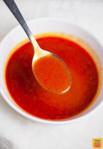 How to make buffalo sauce - buffalo sauce in a white bowl with a spoon