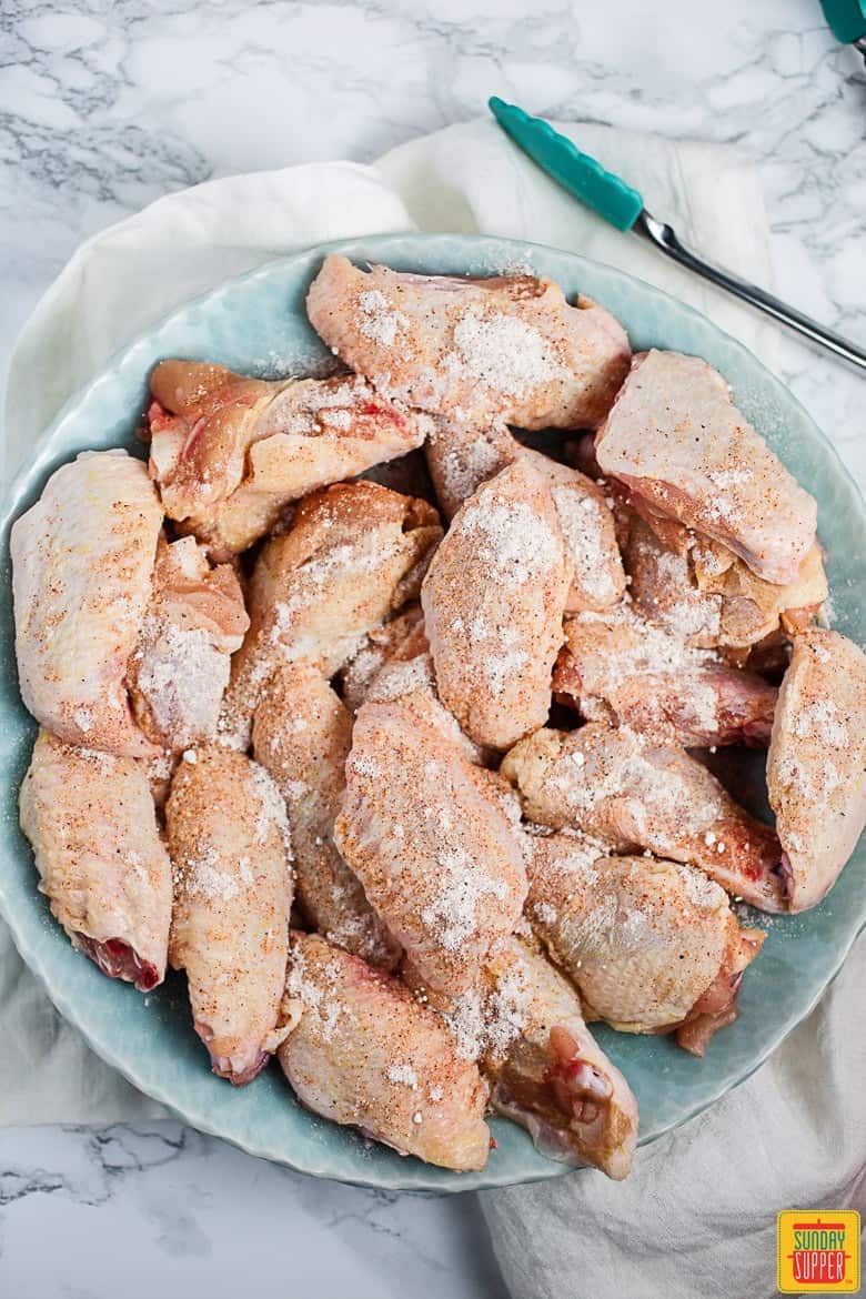 Chicken wings coated with dry ingredients in a bowl