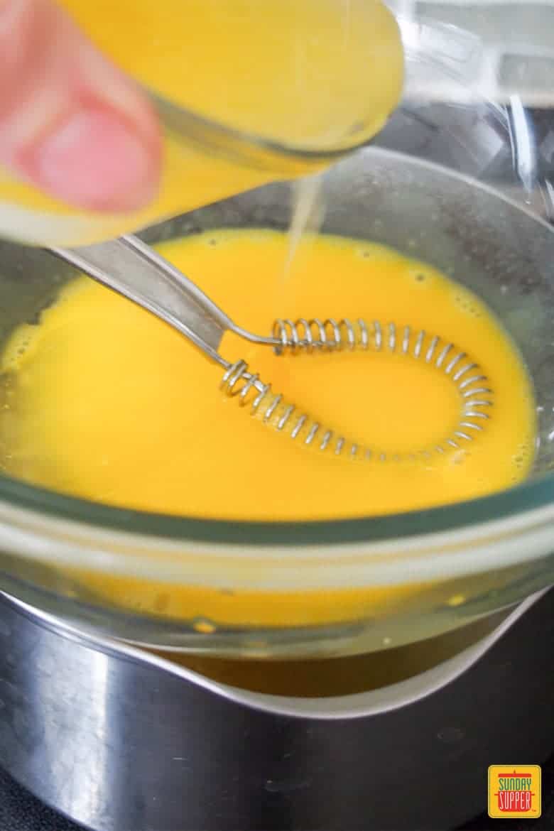 making hollandaise sauce in a bowl with a whisk
