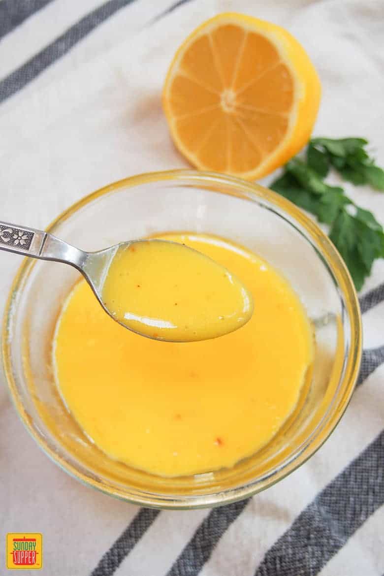 lifting hollandaise sauce out of a glass bowl with a spoon