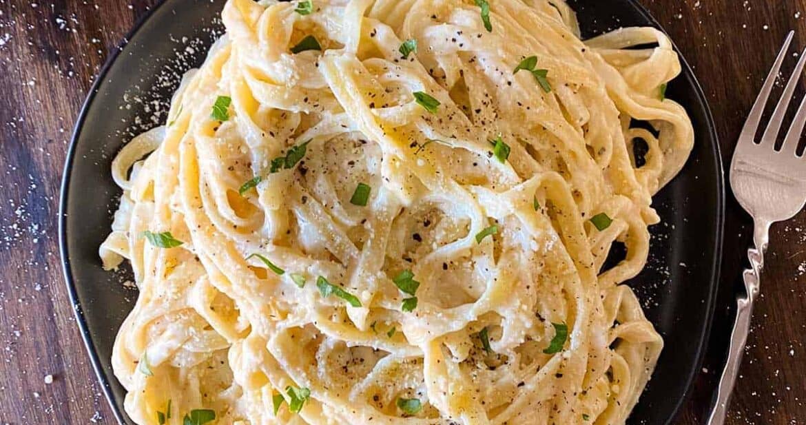 Fettuccine alfredo on a plate with a fork to the side