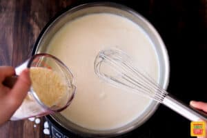 Adding parmesan to alfredo sauce in a skillet