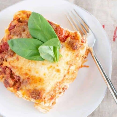 Lasagna for two on a plate with fresh basil