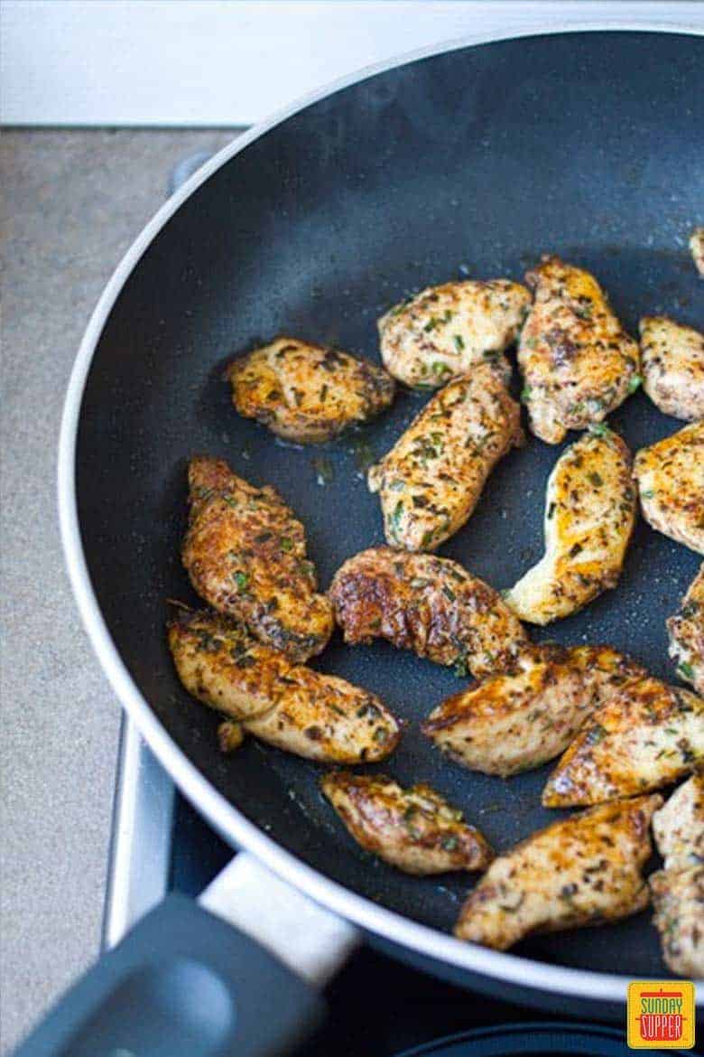 Cooking chicken with seasonings in skillet
