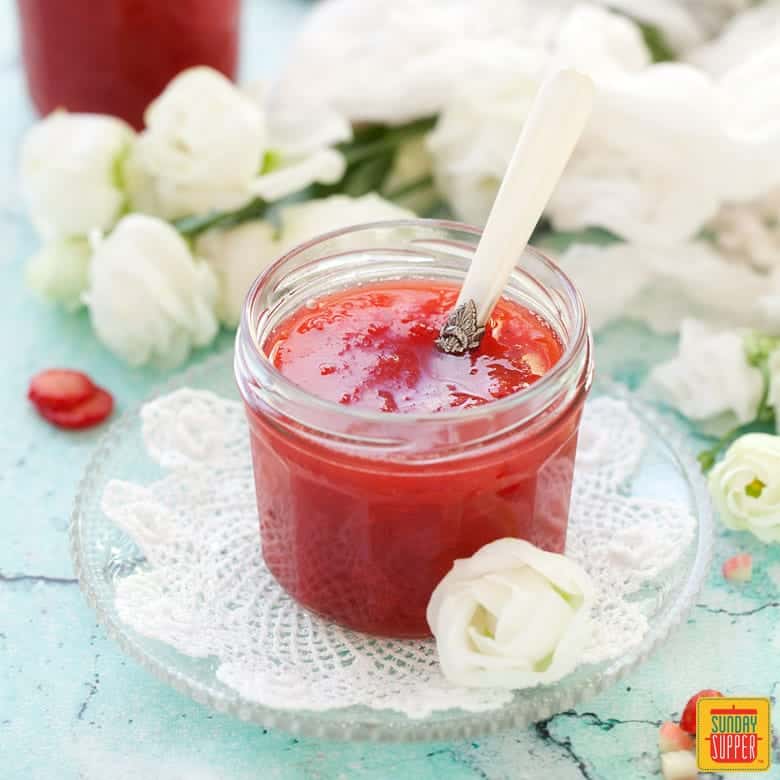 Strawberry Rhubarb Jam in a small jar with a serving spoon
