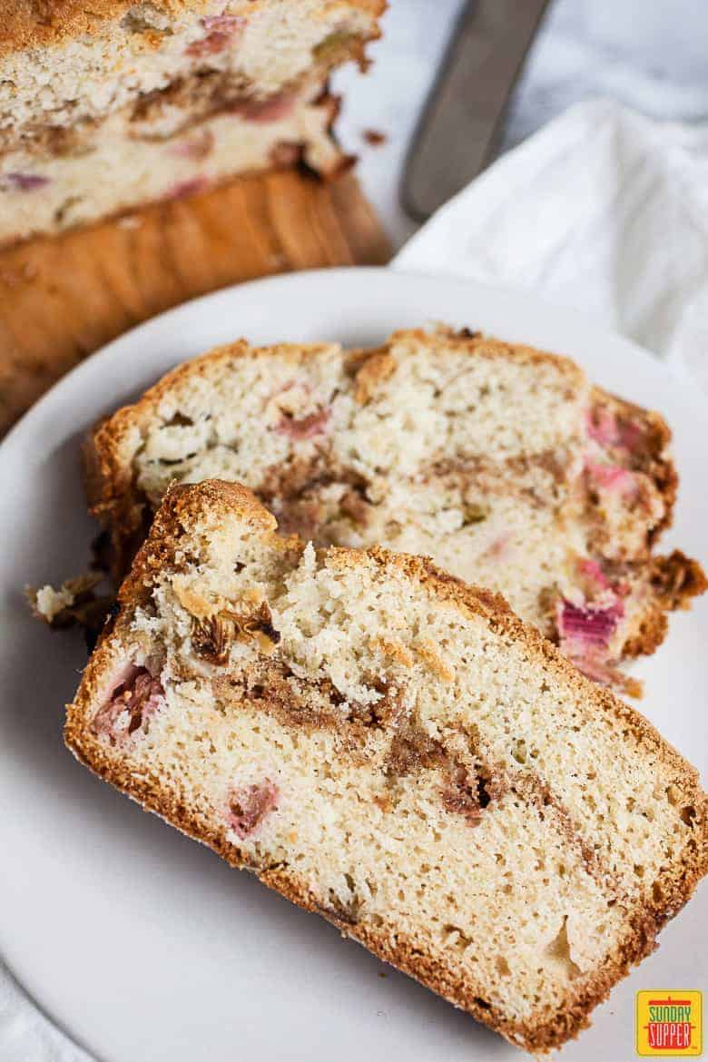 Rhubarb bread: two slices of rhubarb bread on a white plate next to the whole loaf
