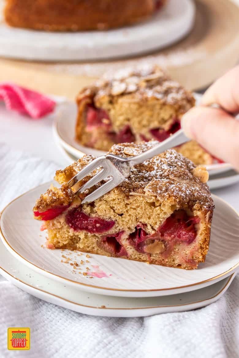 A slice of rhubarb cake with a fork a digging into it