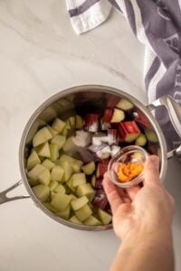 Adding orange zest to apple, rhubarb and sugar in a saucepan