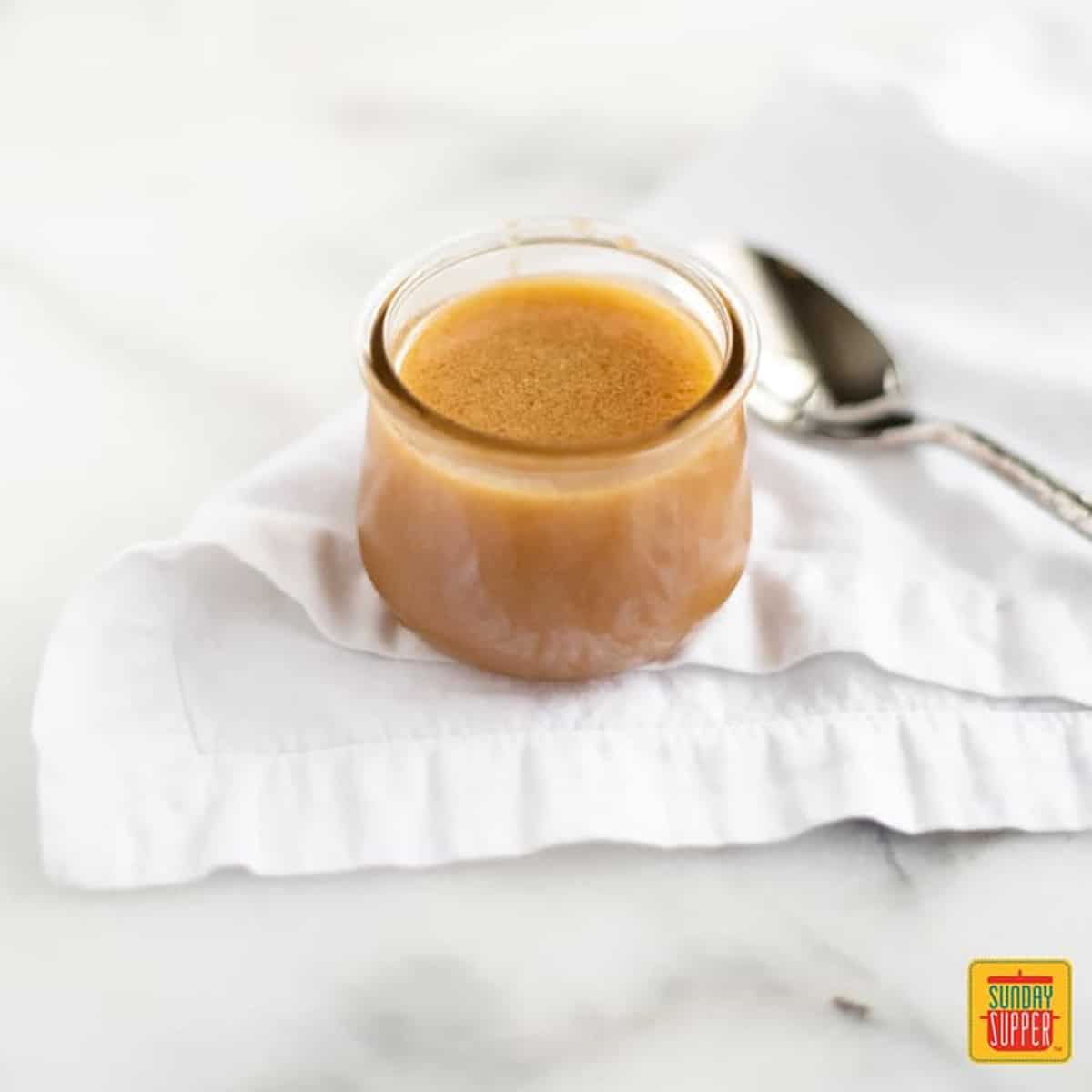 Butterscotch sauce recipe in a jar with a spoon on a white towel