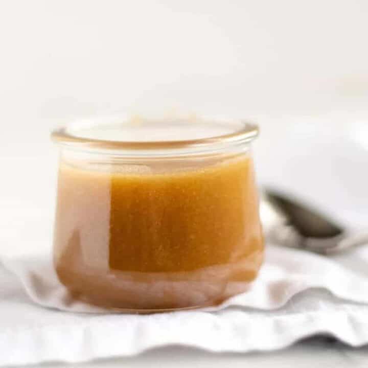 Butterscotch sauce recipe in a glass jar with a spoon and white towel