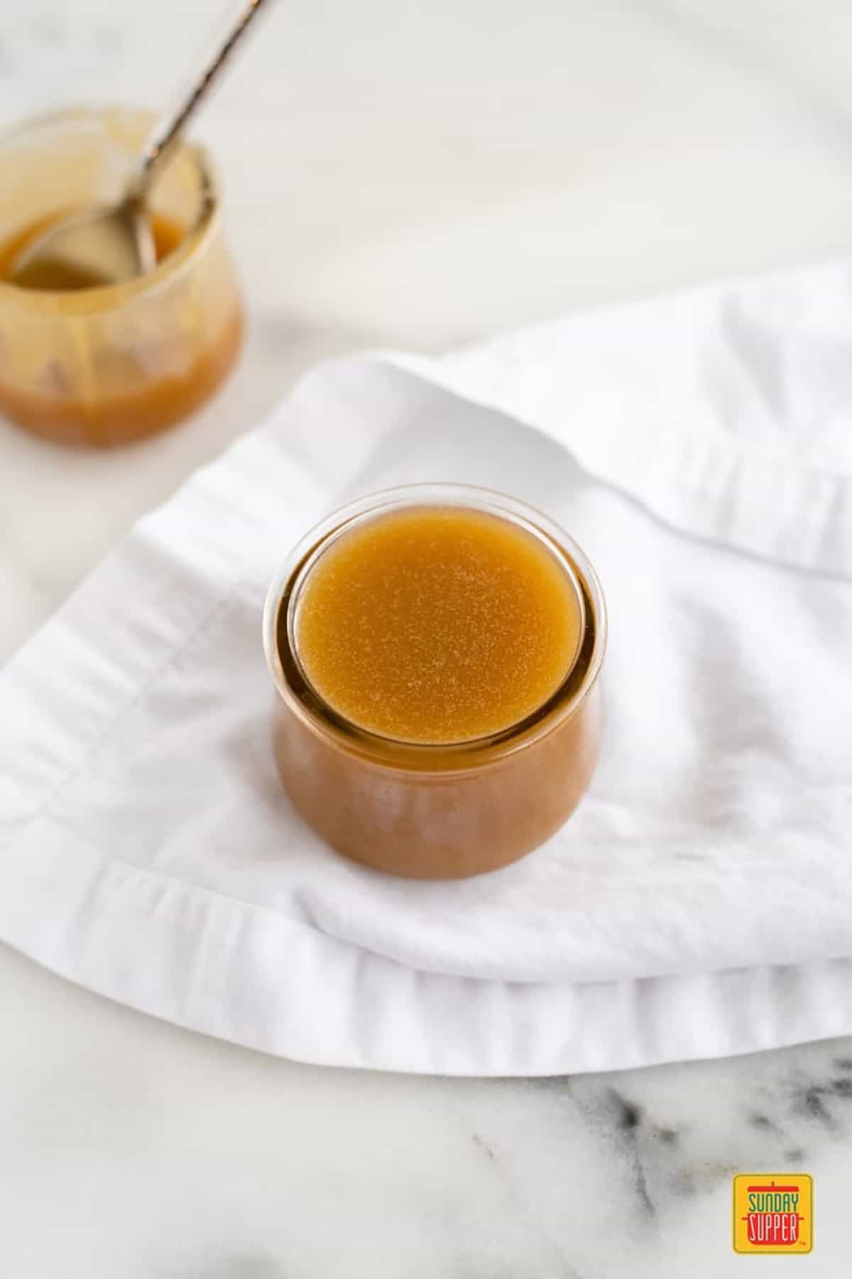 Butterscotch sauce in two glass jars with a spoon in one