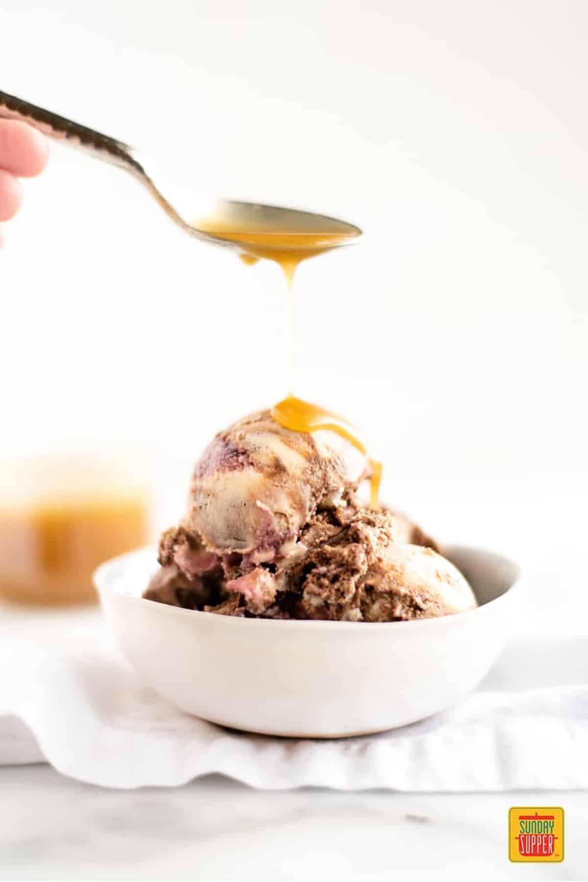 Topping ice cream with butterscotch sauce on a spoon