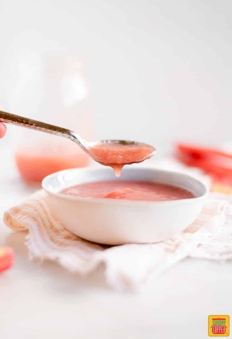 Rhubarb sauce in a white bowl with a spoonful of sauce