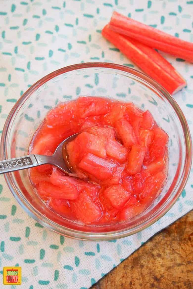 Stewed rhubarb in a glass jar with a spoon in it, ready to enjoy