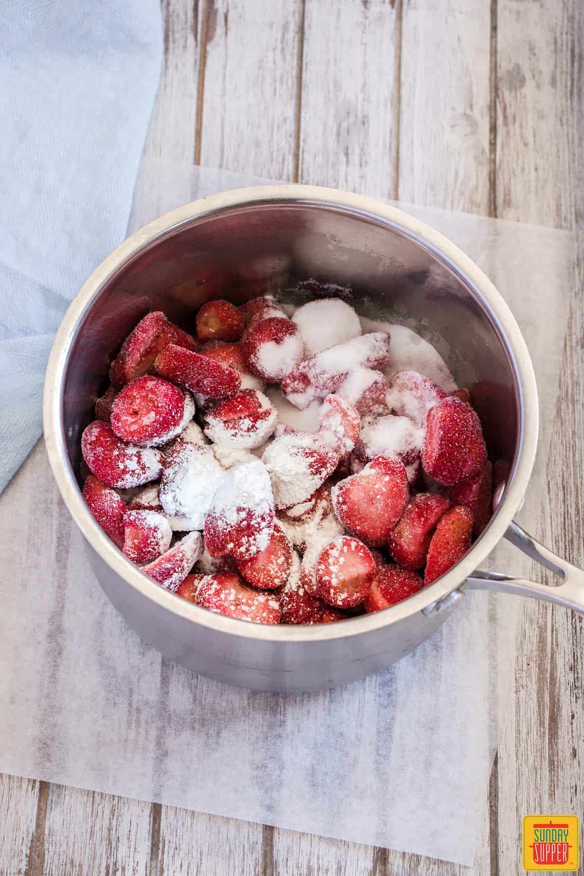 Strawberries with sugar in a deep pot to cook down into strawberry sauce recipe