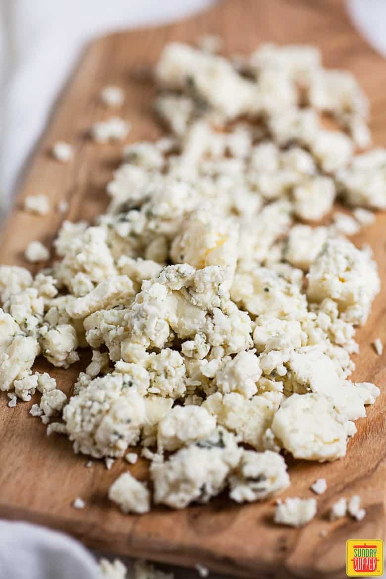 How To Make Blue Cheese Dressing: blue cheese crumbles on a cutting board