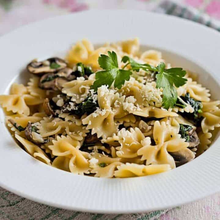 Mushroom spinach pasta on a white plate with parmesan on top