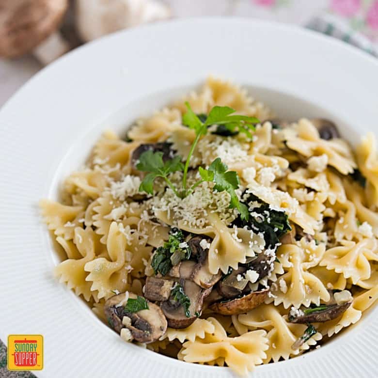 Mushroom Spinach Pasta on a white plate with fresh parsley and Parmesan