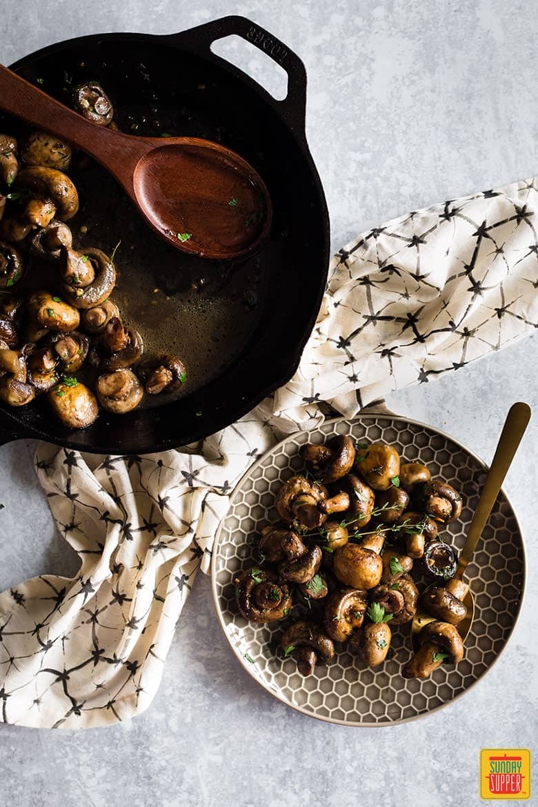 Button mushrooms fresh out of the pan served on a brown plate with a hexagonal pattern
