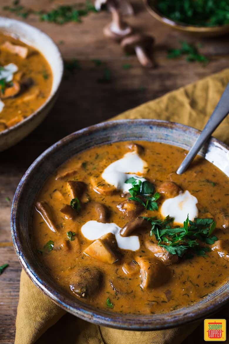 hungarian mushroom soup topped with sour cream in bowls with a spoon, ready to eat