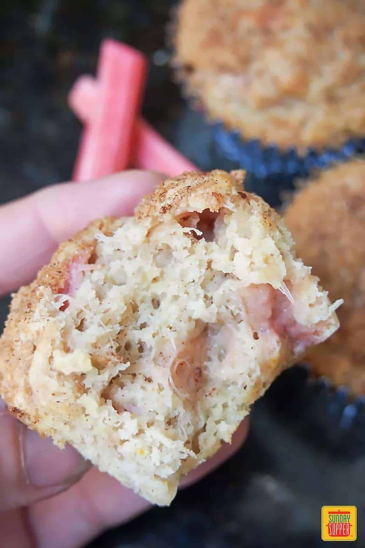 Holding a rhubarb muffin with a bite taken out of it
