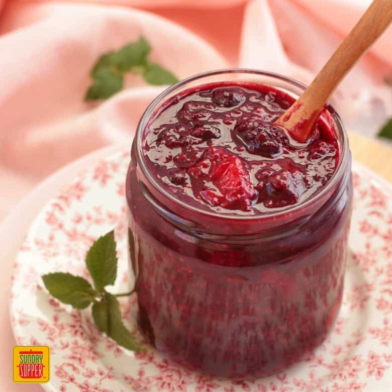 Finished Berry Compote in a Glass Jar with a wooden spoon