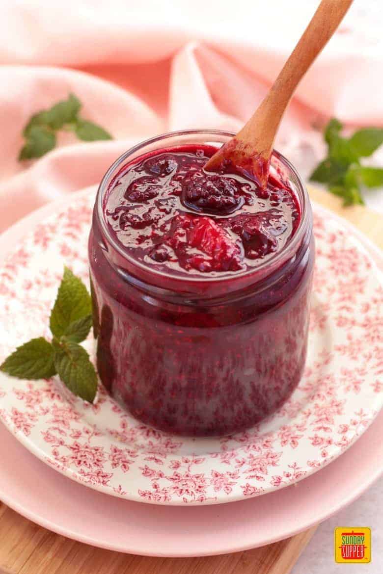 Fresh Berry Compote with Mint in a jar on a floral decorated plate